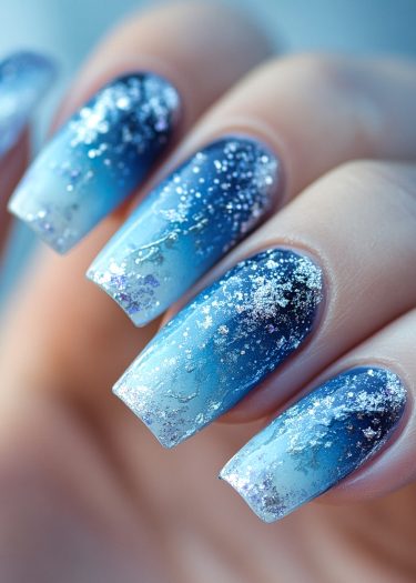 Stunning blue gradient glitter nails with celestial designs and holographic accents for glamorous looks.