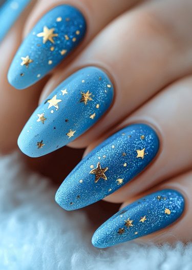 Elegant blue gradient nails with glitter and golden star decals create a celestial design.