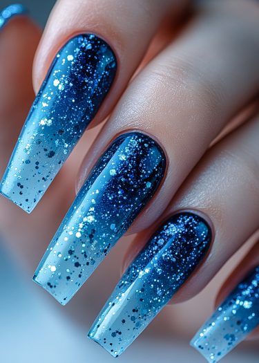 Stunning blue ombre stiletto nails with sparkling glitter design for elegant nail art.