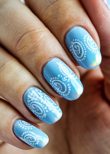 Elegant pastel blue nail art featuring intricate white paisley designs for a modern touch.