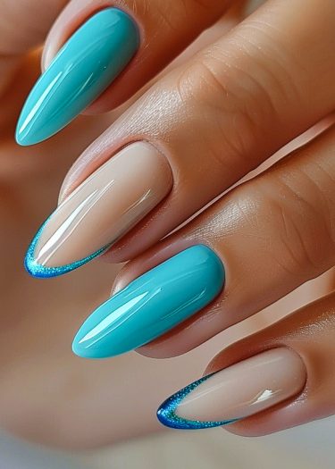 Elegant almond-shaped nails with turquoise and blue glitter gradients for a trendy manicure.