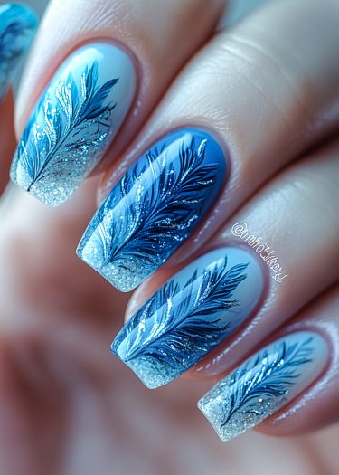 Elegant blue and white gradient feather nail art with metallic shimmer and glossy finish.