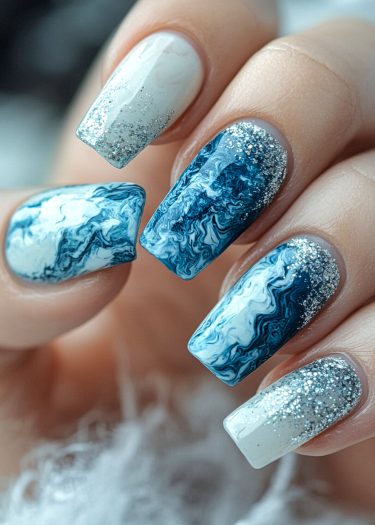 Elegant blue and white marble nail art with silver glitter for a stunning manicure.