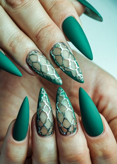 Elegant matte green stiletto nails with intricate lace patterns and metallic accents.