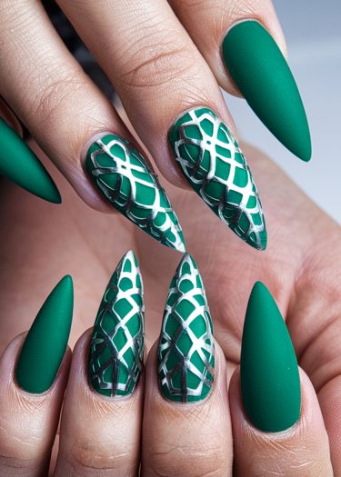 Stiletto nails featuring bold emerald green with matte and glossy textures and intricate designs.