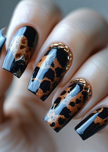 Glamorous black leopard print nails with copper accents and gold chain embellishments for elegant style.