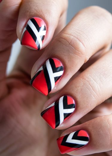 Bold red geometric nail art with black and white designs, showcasing elegant manicure aesthetics.