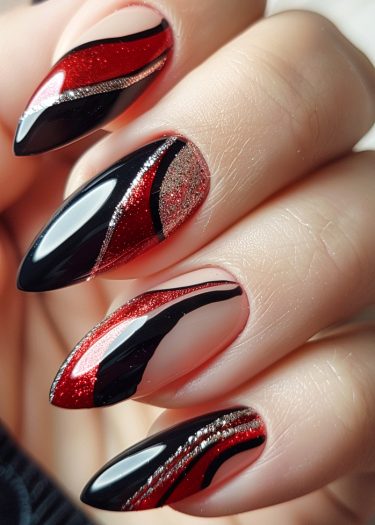 Bold almond-shaped nails feature intricate black and red designs with glitter accents for a stunning look.