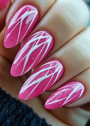 Vibrant pink almond stiletto nails with artistic white designs on a manicured hand.