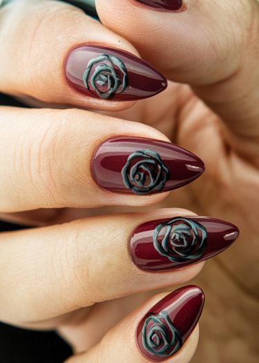 Elegant burgundy almond nails with 3D rose details, perfect for sophisticated occasions.