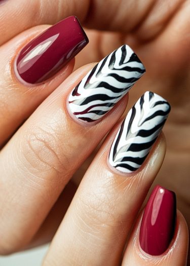 Elegant burgundy nails with playful zebra patterns for stylish nail art creativity.