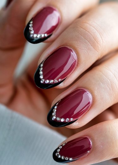 Elegant burgundy and black nail art with rhinestones for a glamorous manicure.