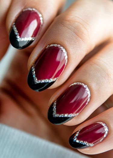 Chic burgundy nails with black tips and silver glitter for a sophisticated manicure.