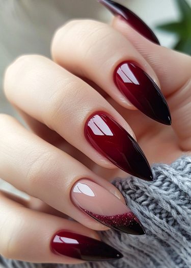 Elegant burgundy stiletto nails with glittery ombre design, showcasing modern nail art trends.