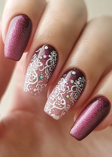 Elegant burgundy manicure with ombre design, lace patterns, and sparkling rhinestones.