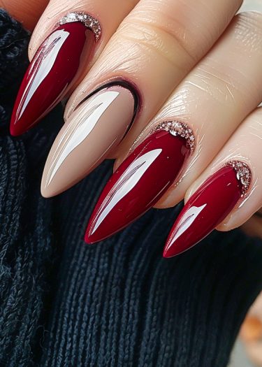 Stunning burgundy stiletto nails with glitter accents and contrasting nude design, showcasing elegant nail art.