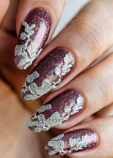 Elegant burgundy glitter nail art with intricate white lace designs for a glamorous look.