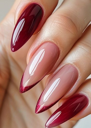 Elegant burgundy stiletto nails with glitter, showcasing sophisticated nail art and ombre design.