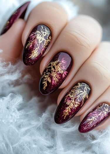 Elegant burgundy nails with gold and pink foliage design, showcasing intricate nail art.