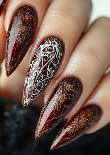 Elegant burgundy nail art with intricate gold spider web and white lace designs.