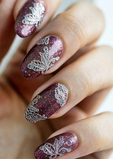 Burgundy lace nail art with glitter, featuring elegant almond-shaped designs for a luxurious look.