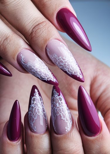 Elegant burgundy almond-shaped nails with intricate white lace design on a pink base.