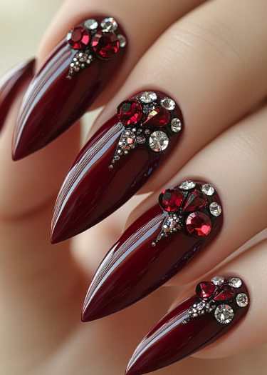 Elegant burgundy stiletto nail art with rhinestones for a sophisticated and glamorous look.