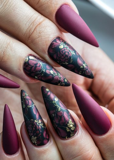 Intricately designed burgundy stiletto nails with floral art and glossy accents for a bold style.