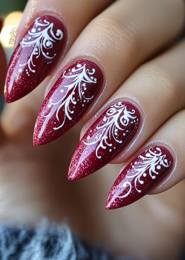 Elegant stiletto nails in deep red with intricate white lace designs and shimmering finish.