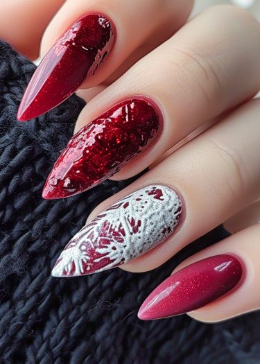 Elegant burgundy stiletto nails with intricate marbled design against cozy dark fabric backdrop.