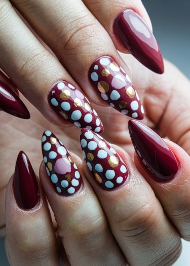 Elegant burgundy almond nails with polka dots, showcasing sophisticated and artistic nail art design.