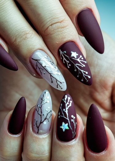 Elegant burgundy stiletto nails with floral art and iridescent accents for a chic look.