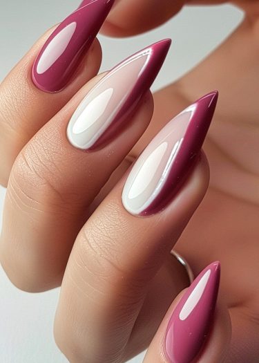 Elegant stiletto nails with burgundy and creamy white polish showcase intricate nail art design.