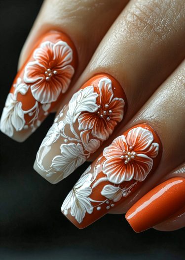 Vibrant burnt orange floral nails with intricate 3D designs, rhinestones, and elegant detailing.