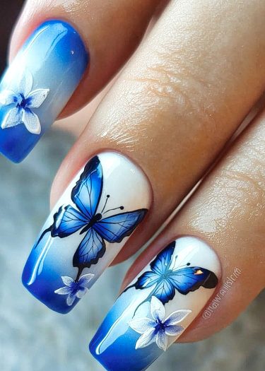 Elegant butterfly and flower nail art with a stunning blue ombre design.