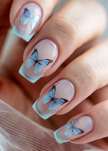 Delicate butterfly nail art with blue designs on translucent pink base, showcasing elegance.