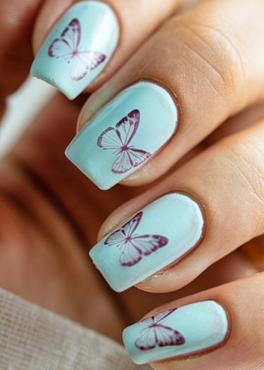 Elegant pastel blue butterfly nail art design with intricate purple butterfly motifs.