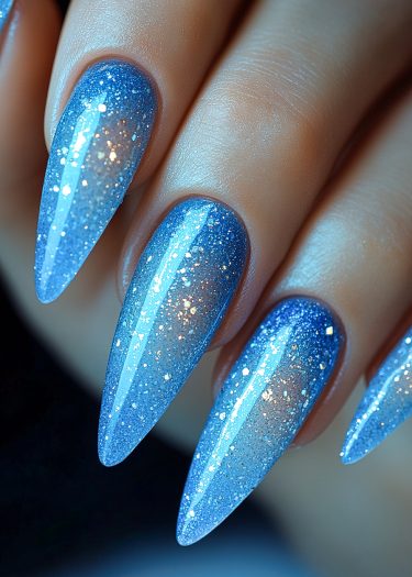 Stunning celestial blue glitter stiletto nails showcase elegance and modern nail art design.