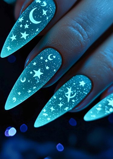 Celestial glow nails with stiletto design featuring moons and stars in vibrant blue hues.