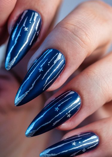 Elegant blue almond-shaped nails with silver shooting star designs for a celestial manicure.