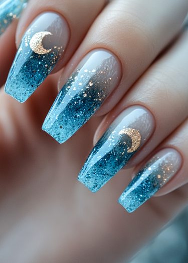 Stunning celestial nail art with ombré blue design, gold crescent moons, and glitter accents.