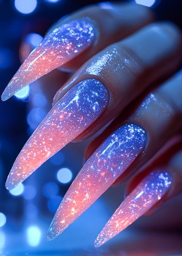 Stunning stiletto nails with celestial ombre design and glitter, showcasing vibrant sunset colors.