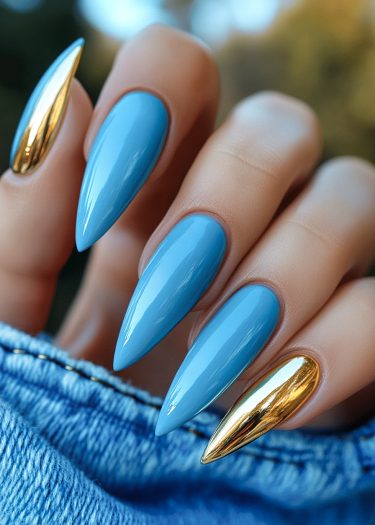 Glamorous cerulean and gold nail design with long, pointed stiletto shapes for a chic look.