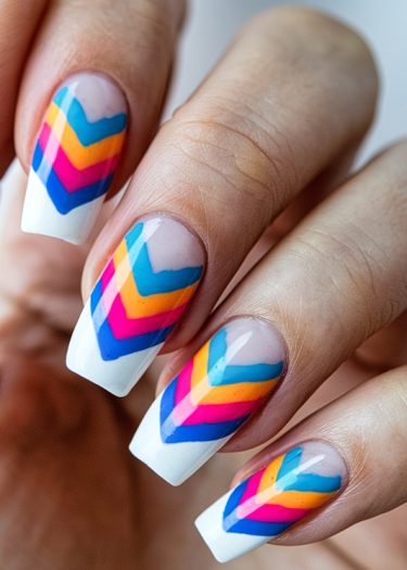 Colorful chevron nail art design on long, manicured nails, showcasing vibrant geometric patterns.