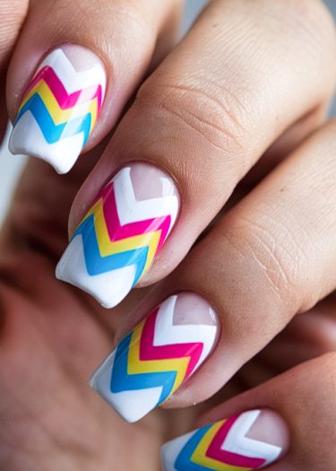 Vibrant chevron nail art in fuchsia, yellow, and blue on square-tipped nails.