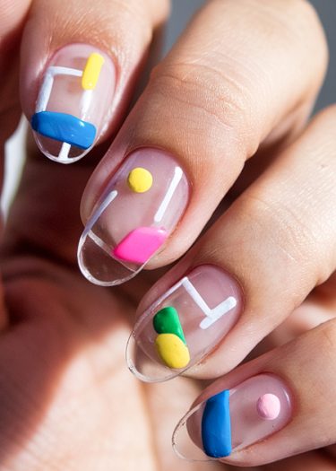 Vibrant geometric nail art with abstract patterns in bold colors on glossy nails.