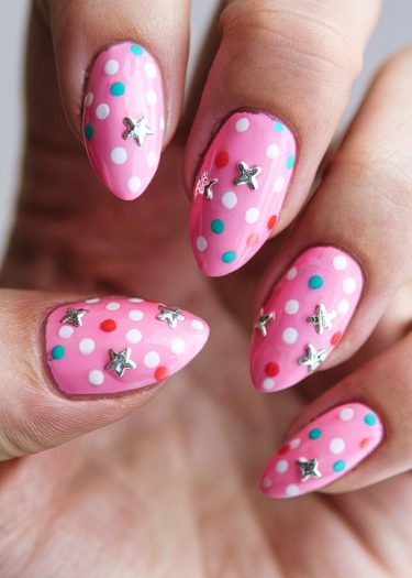 Vibrant pink almond nails with colorful polka dots and silver stars for playful nail art.