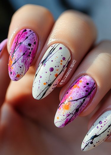 Vibrant colorful splatter nail art with an artistic, glossy finish on almond-shaped nails.