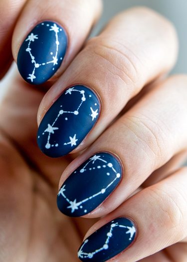 Elegant constellation nail art design on deep navy blue base, showcasing intricate star patterns.