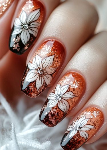 Elegantly manicured copper-orange nails with floral designs and sparkling rhinestones.